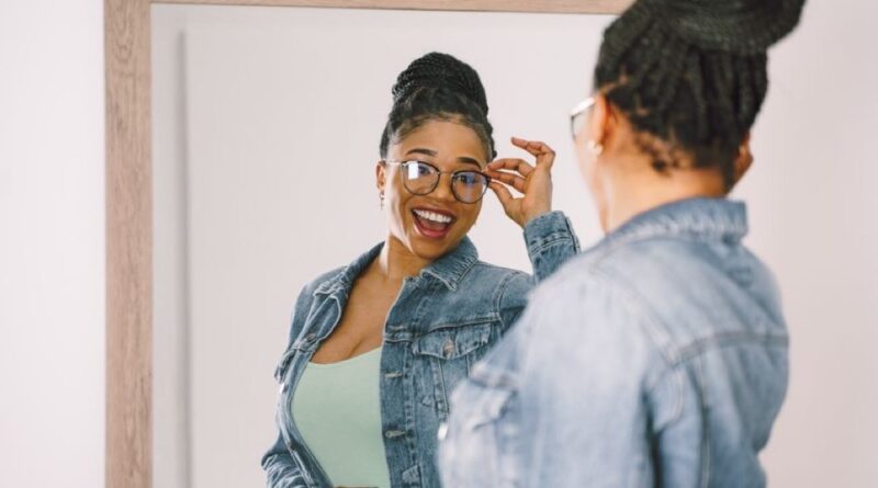 Mulher negra sorrindo, se olhando no espelho